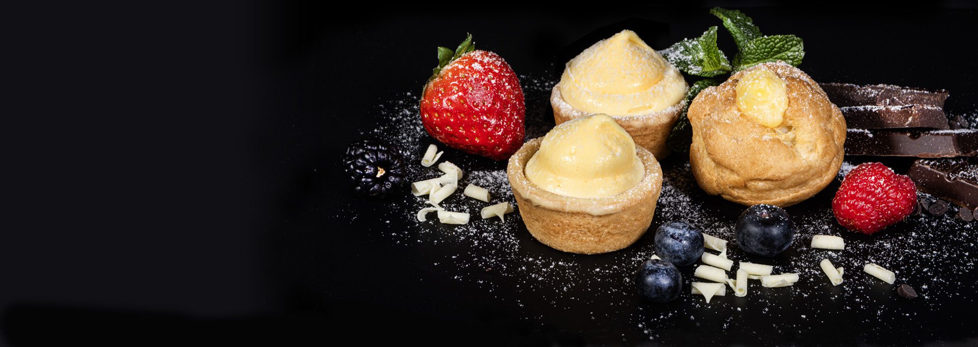 Ambientata di due tartellette ed una bignolina alla crema pasticciera con decorazioni di mirtilli, riccioli di cioccolata bianca, mirtilli e fragole.
